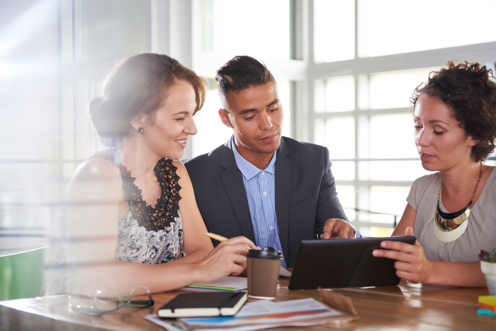colleagues look at a tablet during a meeting